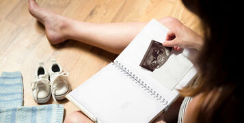 Woman,Placing,Baby's,Sonogram,Into,Baby's,First,Year,Memory,Book.